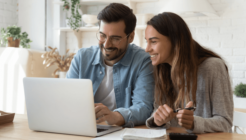 Jovem casal feliz, marido e mulher, usando o computador laptop olhando para a tela de contas de pagamento on-line no aplicativo